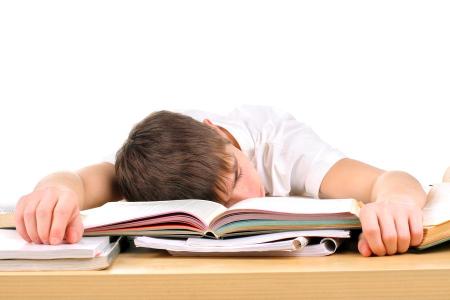 A student falling asleep on his school books due to fatigue