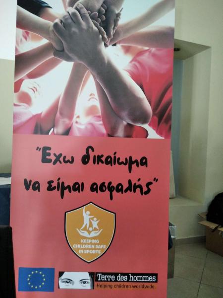 KCSS poster in Greek showing children's hands holding