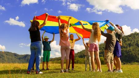 children in a circle holding a parachute