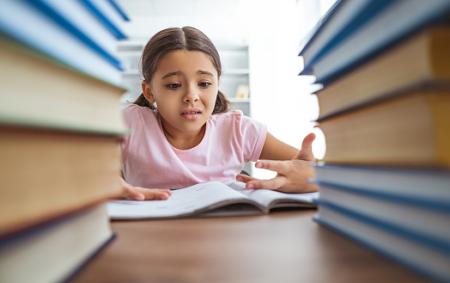 A girl looking frustrated and confused among books. 