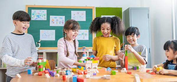 Children playing colorful blocks in classroom.