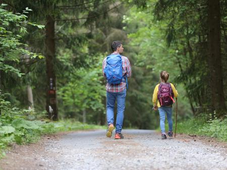 father and daughter walking in a forest