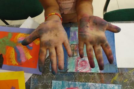 illustrative: child showing her hands after drawing and painting